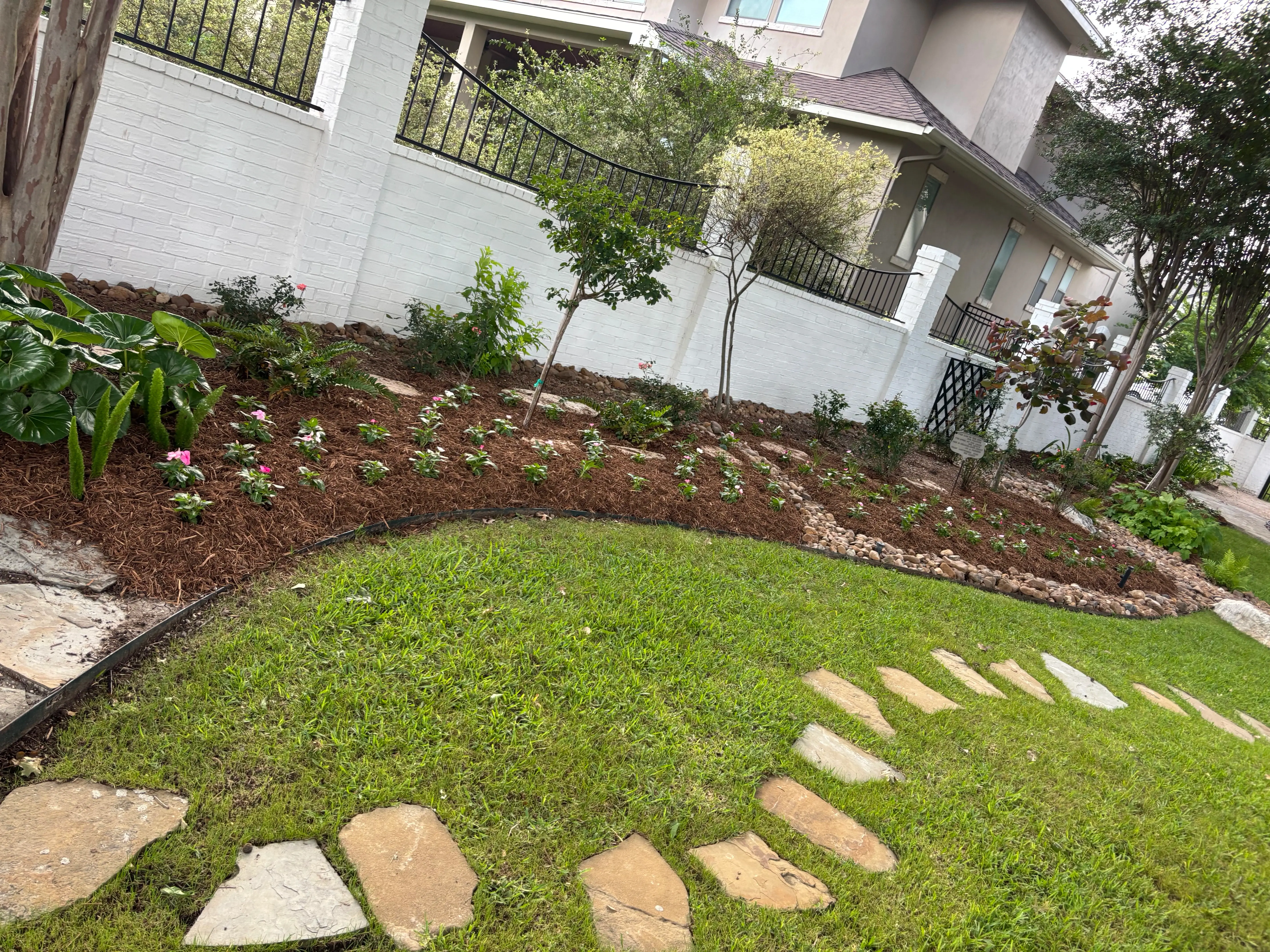Stone path with a flower bed alongside the fence