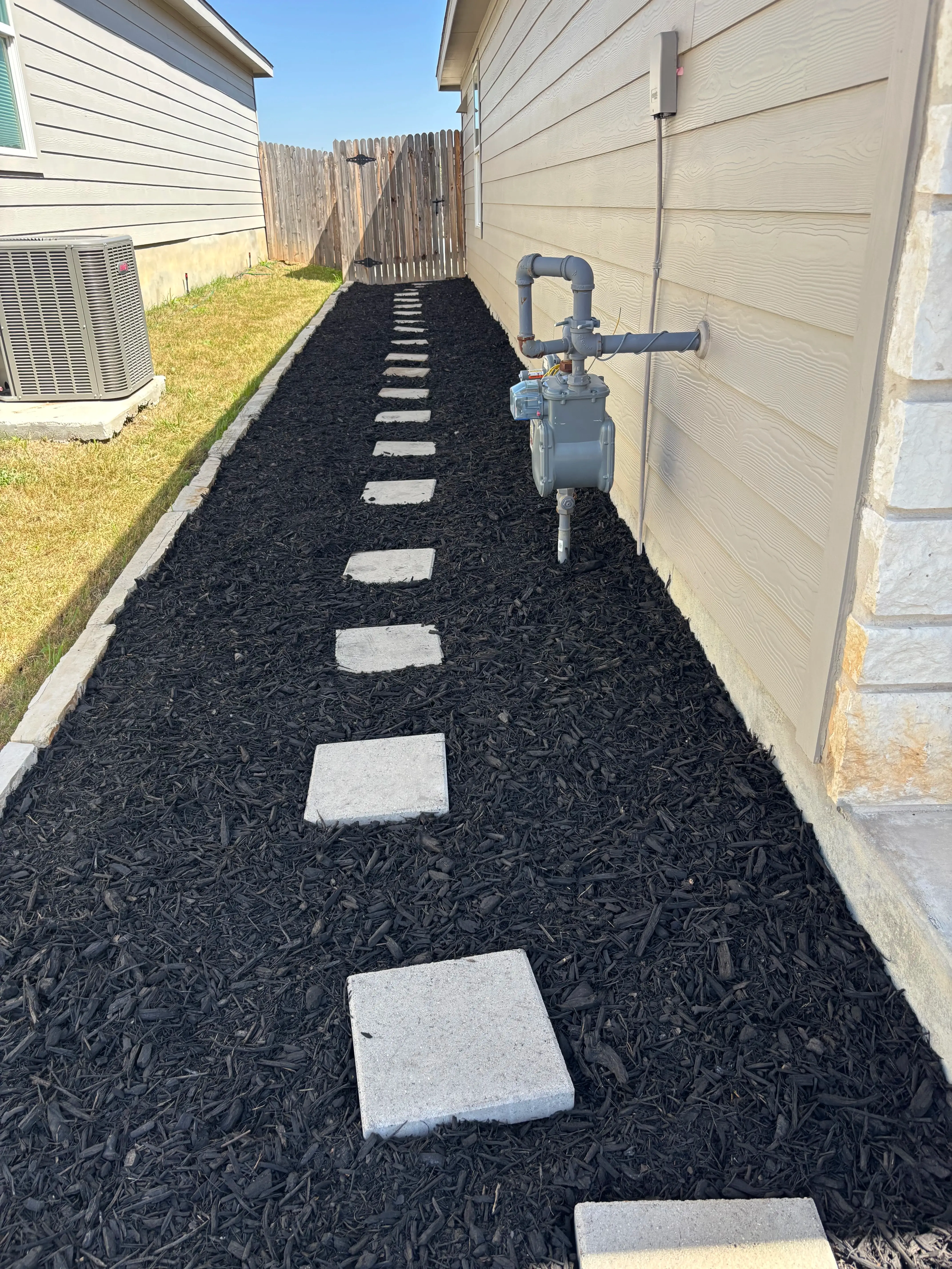 Mulch pathway along the side of a house.